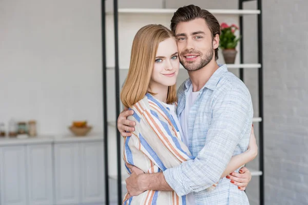 Jovem casal abraçando uns aos outros e olhando para a câmera — Fotografia de Stock