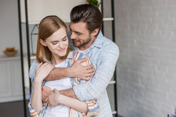 Vue de face du jeune couple souriant s'embrassant — Photo de stock