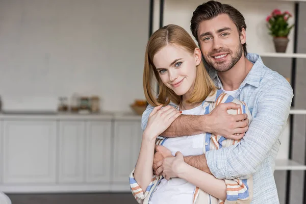 Smiling young man hugging attractive girlfriend — Stock Photo