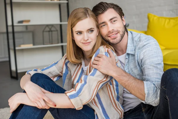 Elegante pareja joven sentada en el suelo en la sala de estar - foto de stock