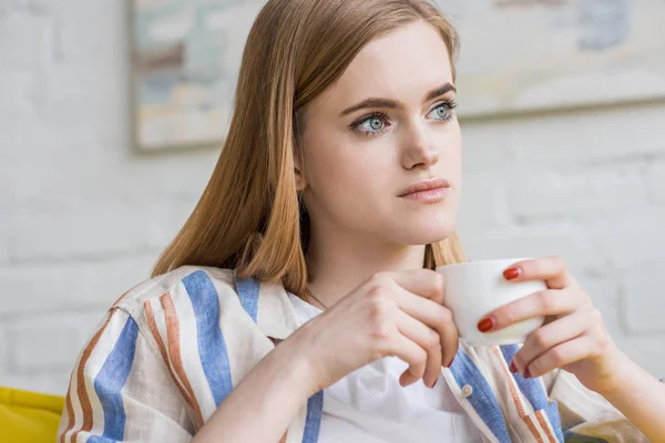 Joven atractiva mujer sentada con taza de café - foto de stock