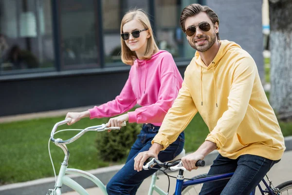 Pareja con estilo en gafas de sol a caballo en bicicletas — Stock Photo