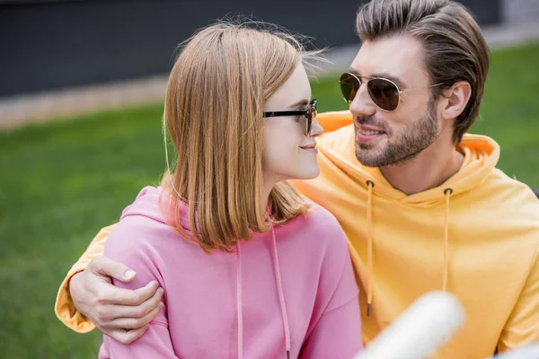 Elegante pareja joven en gafas de sol mirándose entre sí - foto de stock