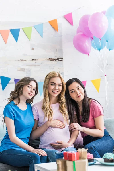 Smiling multicultural friends and pregnant woman looking at camera during baby-party — Stock Photo