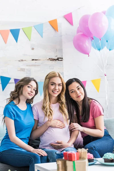 Amici multiculturali sorridenti e donna incinta guardando la fotocamera durante la festa del bambino — Foto stock