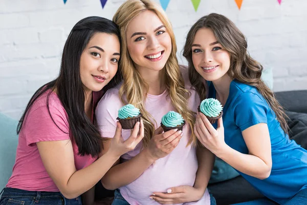 Portrait d'amis multiculturels et de femmes enceintes avec des cupcakes à la fête de baby shower — Photo de stock