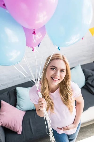 High angle view of beautiful pregnant woman holding balloons and looking at camera at baby-party — Stock Photo