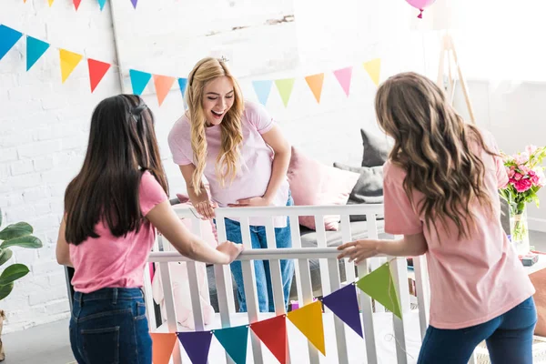 Amigos e mulher grávida olhando para novo berço em baby-party — Fotografia de Stock