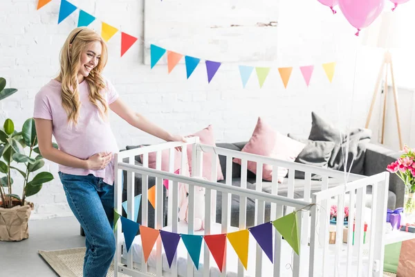 Beautiful pregnant woman looking at new crib at baby-party — Stock Photo