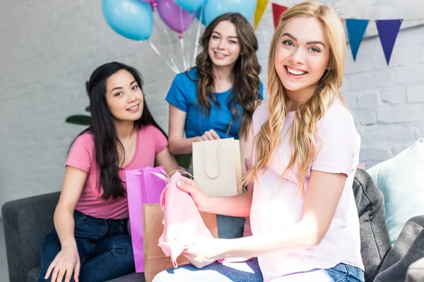 Mujer embarazada sosteniendo regalos de amigos multiculturales en la fiesta del bebé - foto de stock