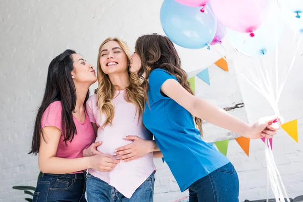 Multicultural friends kissing smiling pregnant woman at baby-party — Stock Photo
