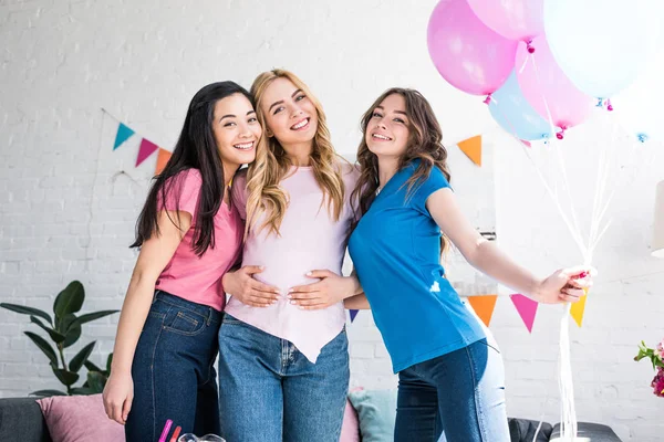 Мультикультурные друзья и беременная женщина позируют с воздушными шарами на вечеринке в честь рождения ребенка — стоковое фото