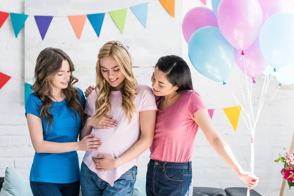 Amigos multiculturales y mujeres embarazadas tocando el vientre en la fiesta del bebé - foto de stock