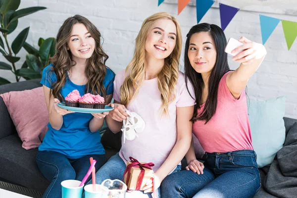 Multicultural friends and pregnant woman taking selfie with smartphone at baby-party — Stock Photo