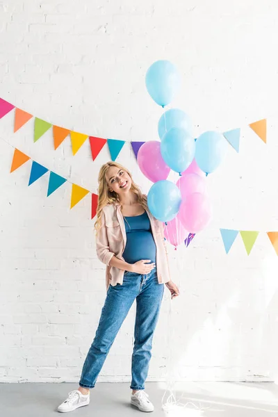 Sonriente hermosa embarazada mujer celebración paquete de globos en fiesta de la ducha del bebé - foto de stock