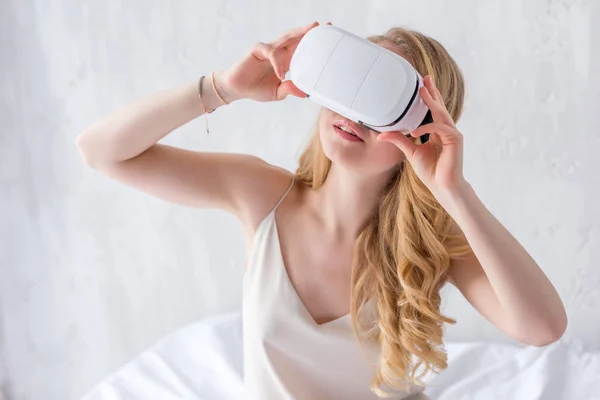 Femme élégante utilisant casque de réalité virtuelle sur le lit — Photo de stock