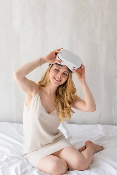 Smiling woman using virtual reality headset in bedroom — Stock Photo