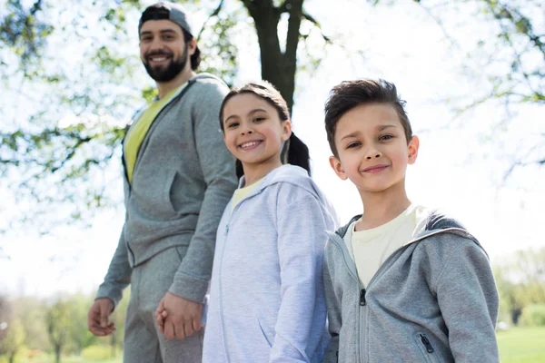 Enfants souriants avec père dans le parc — Photo de stock