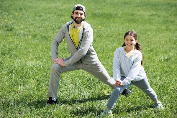 Отец и дочь занимаются физическими упражнениями на лугу в парке — стоковое фото