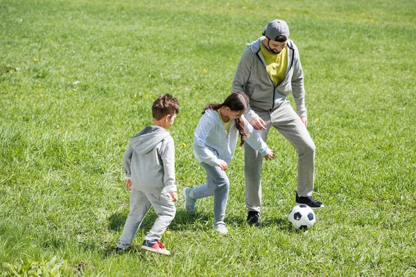 Souriant père jouer au football avec fille et fils dans le parc — Photo de stock