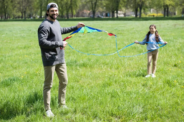 Padre e hija con cometa en prado herboso en el parque - foto de stock