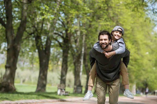 Feliz padre haciendo paseo a caballo a su hija en el parque — Stock Photo