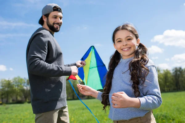 Smiling child with father holding kite on meadow — Stock Photo