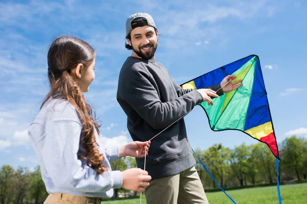Father and daughter holding kite on meadow in park — Stock Photo