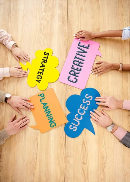 Vue aérienne des gens d'affaires multiraciaux à la table en bois avec des bulles de chat colorées avec des signes de stratégie, de planification, de création et de succès — Photo de stock