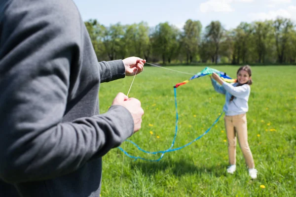 Cropped shot of man holding kite with daughter on meadow — Stock Photo