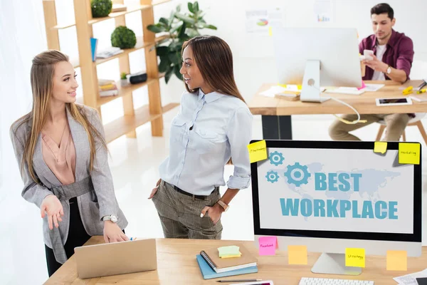Селективная направленность мультикультурных деловых женщин, использующих ноутбуки вместе на рабочем месте в офисе, лучшая надпись на рабочем месте на экране компьютера — стоковое фото