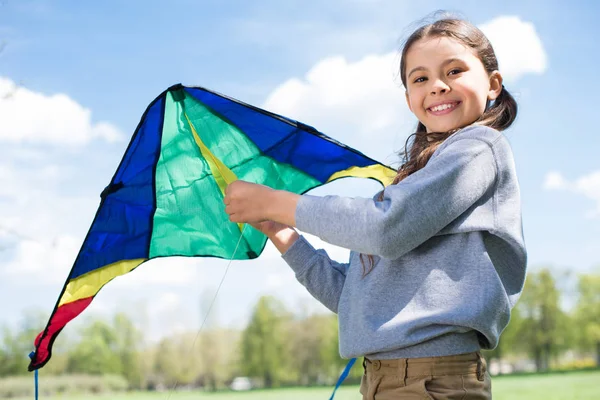 Bambino sorridente che tiene l'aquilone nel parco — Foto stock