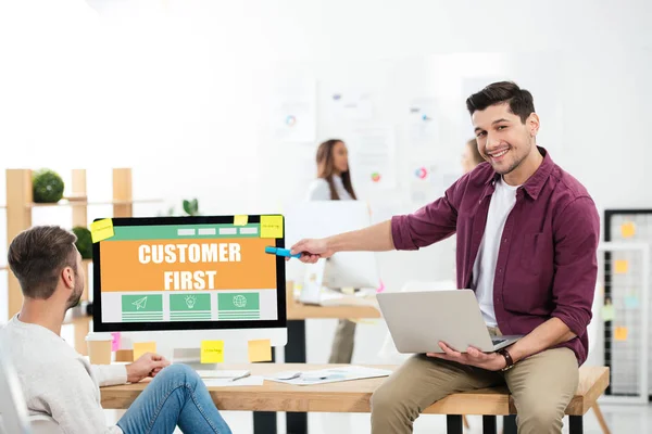 Бізнесмен вказує на споживача перший напис на екрані комп'ютера під час роботи на робочому місці — стокове фото