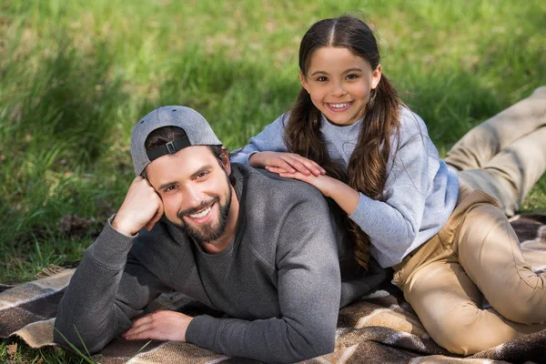 Felice figlia e padre sdraiato sul plaid nel parco — Foto stock