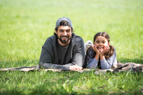 Happy daughter and father laying on plaid in park — Stock Photo