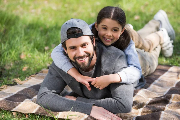 Glückliche Tochter liegt im Park auf dem Rücken ihres Vaters — Stockfoto
