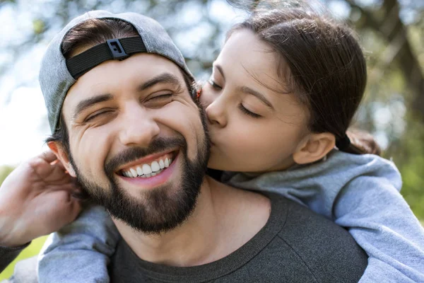 Filha beijando bochecha de pai sorridente — Fotografia de Stock