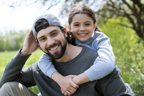 Маленький ребенок обнимает улыбающегося отца в парке — стоковое фото