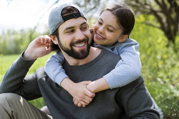 Figlia sorridente che abbraccia il padre da dietro — Foto stock