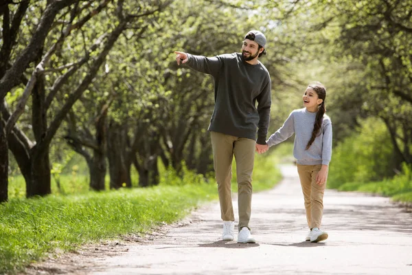 Father pointing by finger to daughter in park — Stock Photo