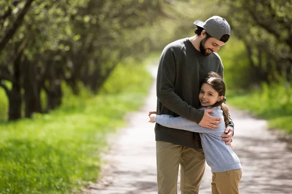 Padre abbracciando figlia sul sentiero nel parco — Foto stock