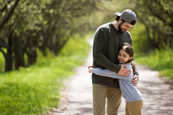 Père embrasser fille sur le chemin dans le parc — Photo de stock