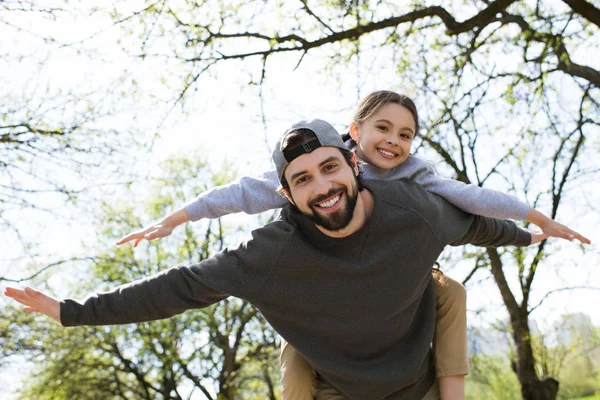 Low angle view of daughter on father back in park — Stock Photo