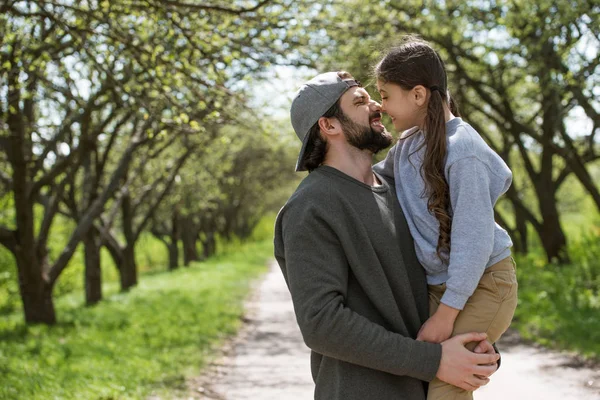 Side view of daughter and father rubbing noses in park — Stock Photo