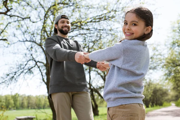 Sorrindo pai e filha de mãos dadas no parque — Fotografia de Stock