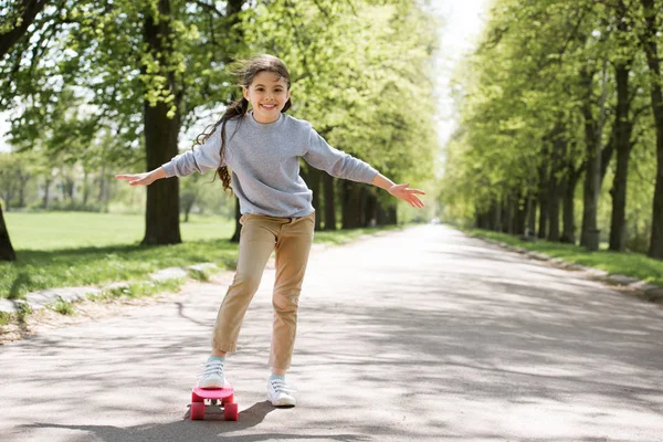 Little child with skateboard on path in park — Stock Photo