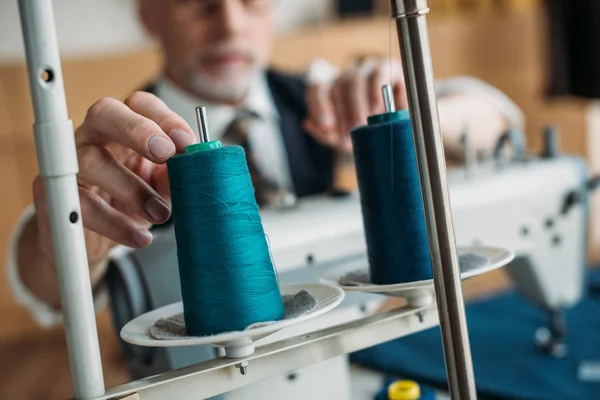 Zugeschnittenes Bild von Senior-Schneiderin, die bei Nähworkshop Fadenspule an Nähmaschine berührt — Stockfoto