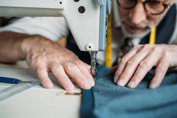 Обрезанное изображение швейной ткани портнихи с швейной машинкой в швейной мастерской — стоковое фото