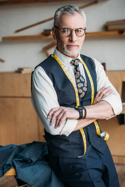 Handsome tailor standing with crossed arms at sewing workshop — Stock Photo