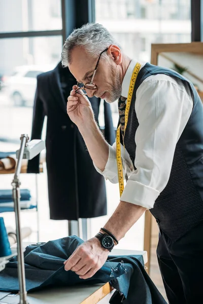 Bello sarto esame panno al laboratorio di cucito — Foto stock